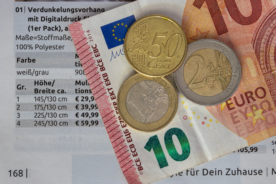 Close-up image of a black calculator with blue functional keys, positioned next to three stacks of British coins on a white surface, representing financial aspects of professional cleaning services. T